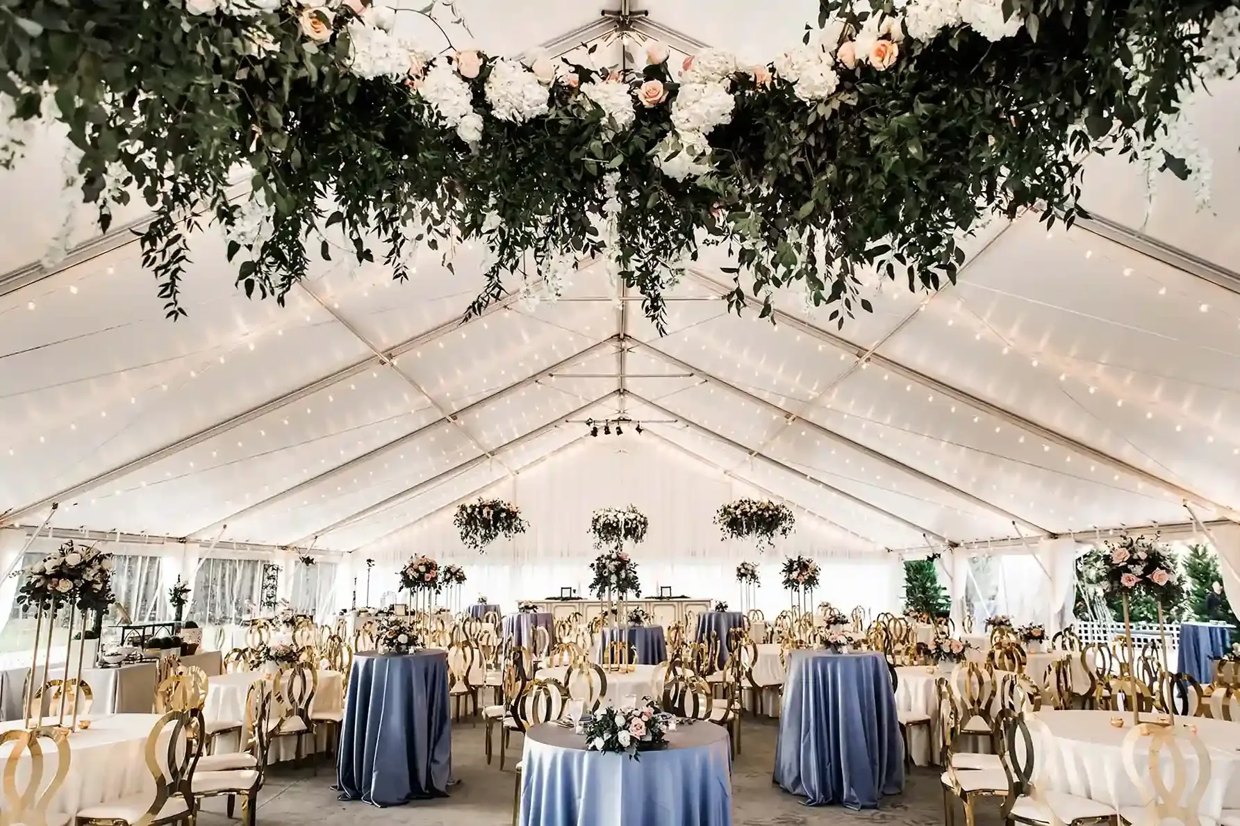 Tent wedding with string lights and greenery chandeliers